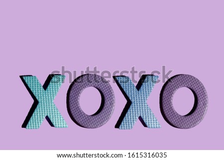 the inscription "XOXO" on Valentine's Day with hard shadows on a purple background
