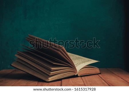 Old book on a red wooden table. Background of green wall.