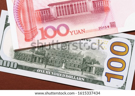One hundred dollars and yuan on a dark background, top view