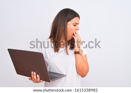 Beautiful young woman working using computer laptop over white background bored yawning tired covering mouth with hand. Restless and sleepiness.