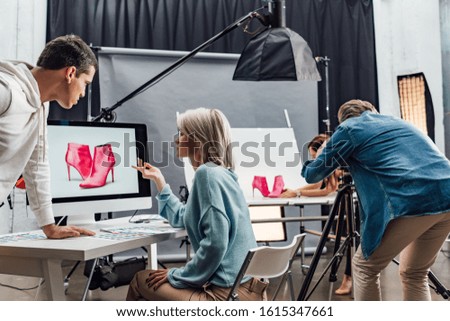attractive art director gesturing near computer monitor with photo of shoes