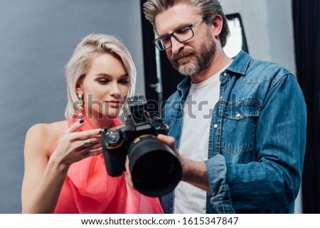 handsome art director holding digital camera near attractive model