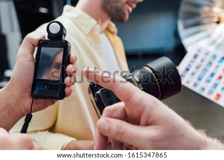 cropped view of art director pointing with finger at light meter