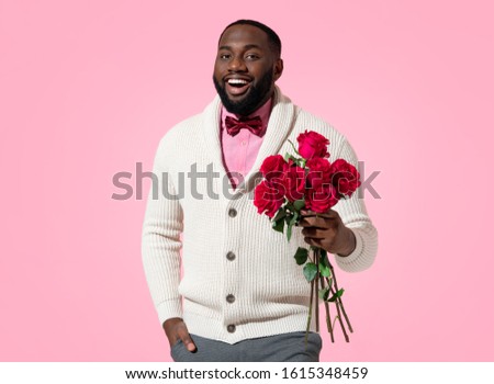Handsome man holds bouquet of roses. Photo of african american man expresses love to someone, romantic feelings on pink background. Be my Valentine