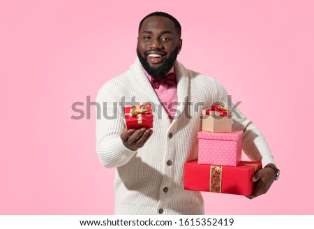 Handsome man gives gifts. Photo of african american man expresses love to someone, romantic feelings on pink background. Be my Valentine