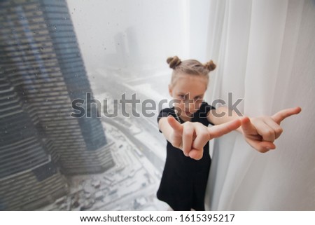 a little girl stands at the window of a skyscraper