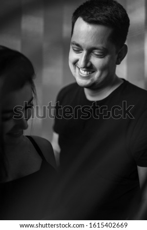 Romantic couple expecting baby, holding hands and touching foreheads while standing together on belly against window at home, free space. Pregnancy, maternity, preparation and expectation concept.