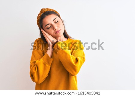 Young beautiful woman wearing yellow sweater and diadem over isolated white background sleeping tired dreaming and posing with hands together while smiling with closed eyes.