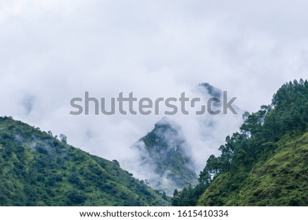 Picture of Himalayas mountains covered with fog. Green hills with forest behind the clouds. Hiking, trekking in Nepal.