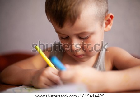 Closeup portrait of cute little boy drawing picture. The beautiful, emotional face of a child of four years. Drawing of emotions. Shallow depth of field