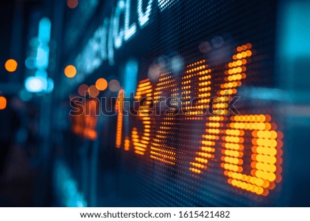Display stock market numbers and graph with city light reflections at the street. Small focus line, some noise. Blurry.