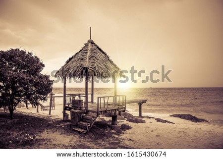 Vintage and retro toning of tropical beach with blue sky and clear sea which including of a wooden umbrella and chair in sunrise time with vintage retro tone. Vacation time as concept.