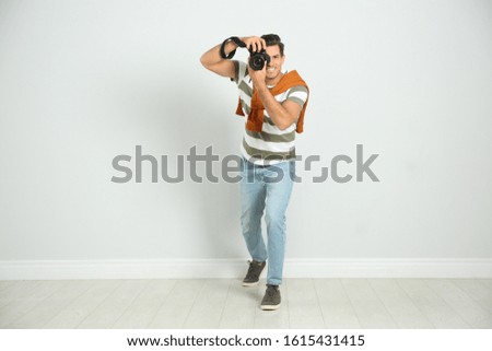 Professional photographer working near white wall in studio