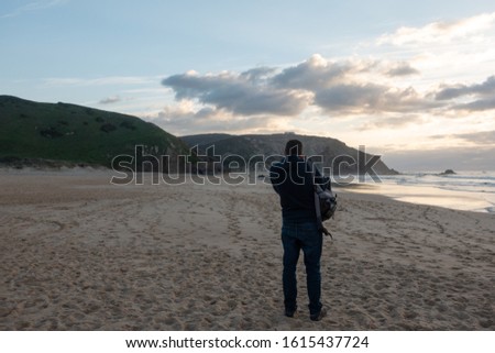 Man taking a photo of Praia do Amado beach in Costa Vicentina, Portugal
