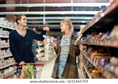 Smiling young adult boyfriend and girlfriend choosing snack together, standing in supermarket with grab and go technology Royalty-Free Stock Photo #1615465759