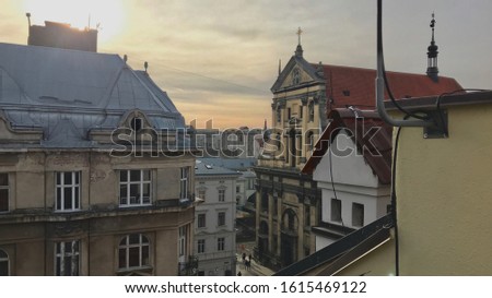 Old ancient European city landscape orange sunset red roof white sky winter evening stock photo