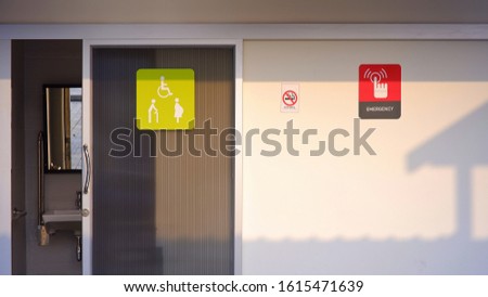 Restroom sign for elderly, disabled, pregnant with no smoking and emergency sign label on sliding door and cement wall of public bathroom 