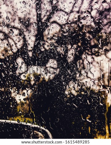 Drops of water from a beautiful summer storm bathe the window of a car during a long journey through the countryside.