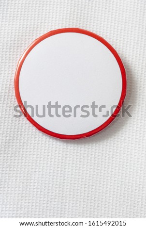 Vertical close-up shot of a round blank campaign button on a white shirt.    Copy space. Royalty-Free Stock Photo #1615492015