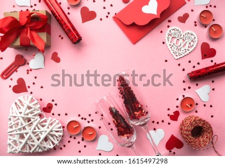 Saint Valentine day. Flat lay arrangement of red handmade felt hearts and gift boxes on pink background. Copy space.