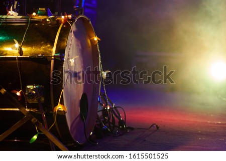 Drum set on stage bass drum close-up in fog and multi-colored lighting