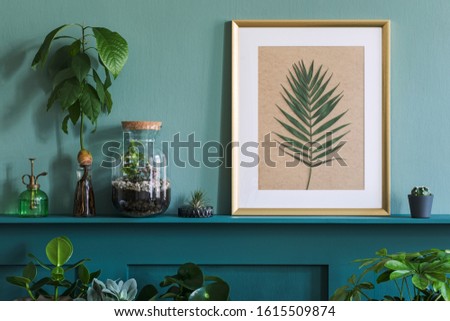 Interior design of living room with gold mock up photo frame on the green shelf with beautiful plants in different hipster and design pots. Elegant personal accessories. Home gardening. Template. 