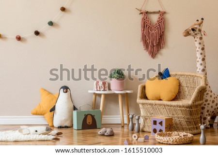 Stylish scandinavian interior of child room with natural toys, hanging decoration, design furniture, plush animals, teddy bears and accessories. Beige walls. Interior design of kid room. Template.