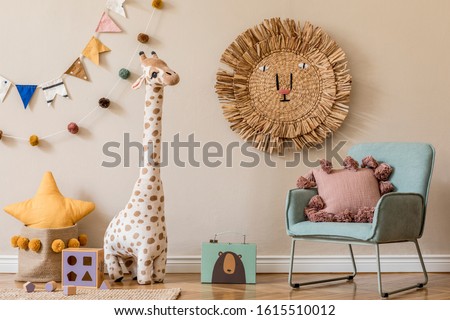 Modern scandinavian newborn baby room with design mint armchair, wooden toys, plush animal and neutral decoration. Hanging cotton balls and flags. Cozy kid room interior with beige walls. Home staging
