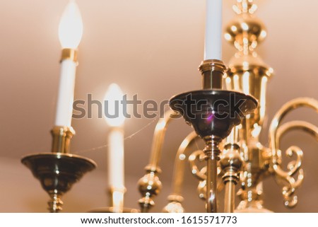 Pictured of a cobweb in a golden defocused chandelier and a closed photo
