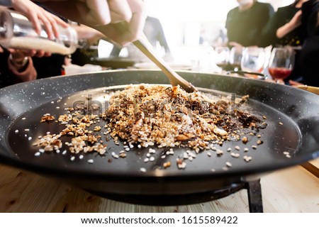 Paella pan with traditional Spanish food usually prepared with rice, meat, seafood. Mixing process