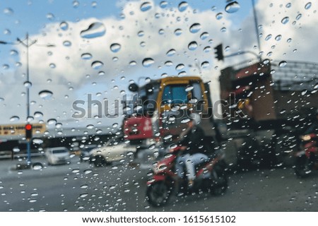 Rain droplets on the glass with cars at the backdrop de focused in bokeh mode.