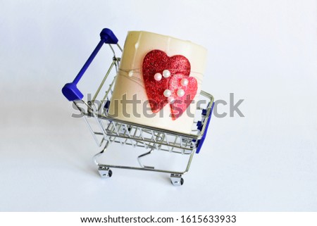 Valentines Day concept. Candle with red hearts glued to it in a shopping trolley. 