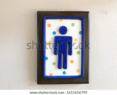 Restroom sign made of ceramic on the wall.