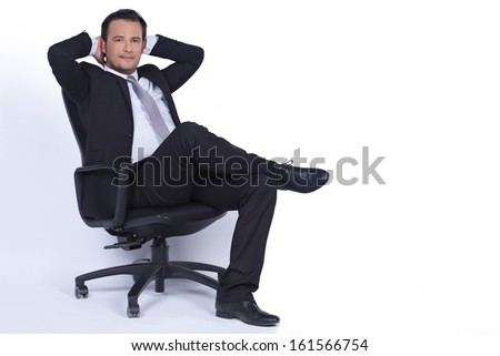 Handsome businessman is sitting on a chair and looking us