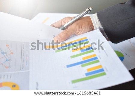 The hand is holding the pen and and analyzing the graph