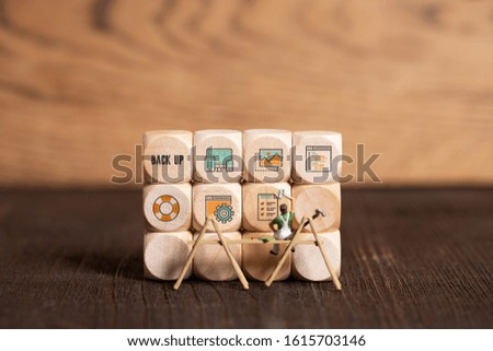 little painter figures and cubes with tech icons on wooden background