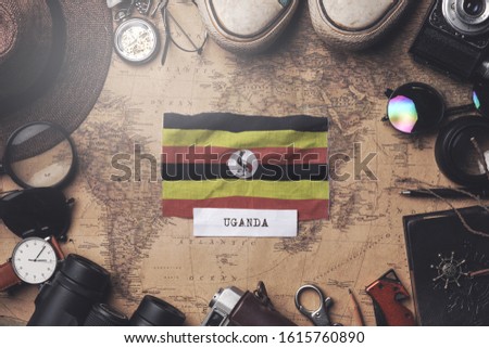 Uganda Flag Between Traveler's Accessories on Old Vintage Map. Overhead Shot