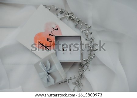 romantic card, simple smooth white gold rings in a silver box on the background of a picture with the inscription love and white tulle
