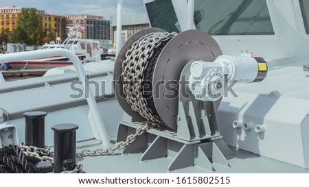 modern winch with a new anchor chain on the deck of the boat