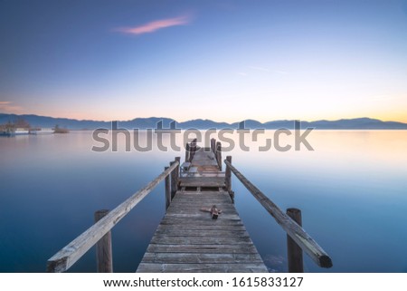 Wooden pier or jetty and lake at sunrise. Long Exposure. Torre del Lago Puccini, Versilia, Massaciuccoli lake, Tuscany, Italy, Europe