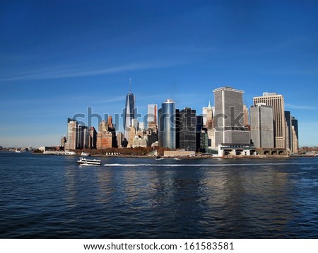 Lower Manhattan, NYC, including the new One World Trade Center Freedom Tower, can be seen across the blue water of the New York Bay at the end of the Hudson River.