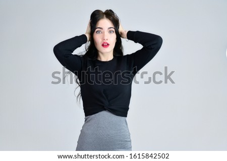Portrait of a brunette girl with a smile with long hair with excellent makeup in a gray dress on a white background in different poses. Concept of business female photo portrait with emotions.