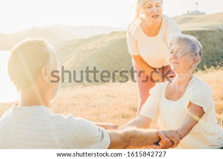 Senior woman helping to stretch senior couple while they doing workout and yoga exercices outdoors. Concept of healthy lifestyle.