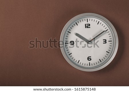 minimalistic white wall clock with light metal on a brown background. time concept.