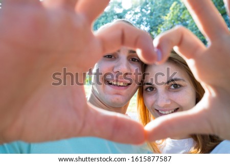 Happy young couple taking selfie outdoors in warm sunny weather.