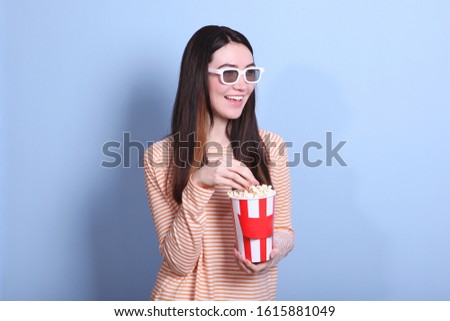 girl with popcorn on a colored background. Watch a movie, 3D movie.
