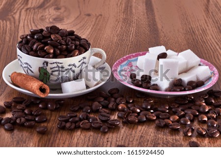 Vintage coffee cup with coffee beans, next to saucer with sugar cubes