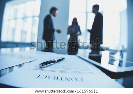Close-up of business contract with pen at workplace on background of office workers interacting Royalty-Free Stock Photo #161596511