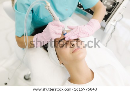 Professional female cosmetologist doing hydrafacial procedure in Cosmetology clinic. Doctor use hydra vacuum cleaner. Rejuvenation And Hydratation. Cosmetology Royalty-Free Stock Photo #1615975843