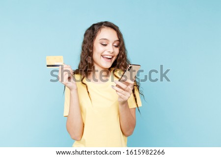Young woman holding phone in the studio and making shopping online.